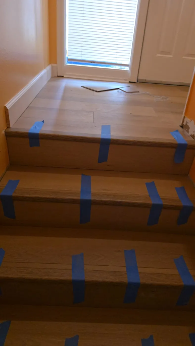 Stair landing with newly installed wood treads and plank flooring at the entry